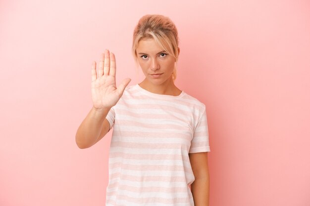 Junge russische Frau isoliert auf rosa Hintergrund, die mit ausgestreckter Hand steht und Stoppschild zeigt und Sie verhindert.