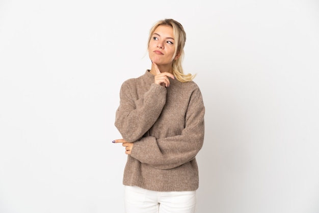 Foto junge russische frau lokalisiert auf weißer wand, die zweifel beim aufblicken hat