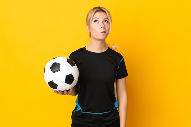 Junge russische Fußballspielerfrau lokalisiert auf Gelb und nach oben schauend