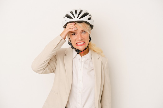 Foto junge russische geschäftsfrau, die fahrradhelm lokalisiert auf weißem hintergrund hält und schockiert ist, hat sich an wichtiges treffen erinnert.