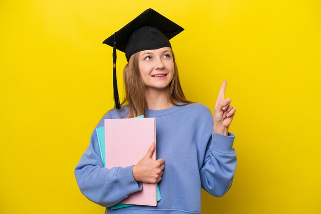 Junge russische Studentin isoliert auf gelbem Hintergrund, die auf eine großartige Idee zeigt