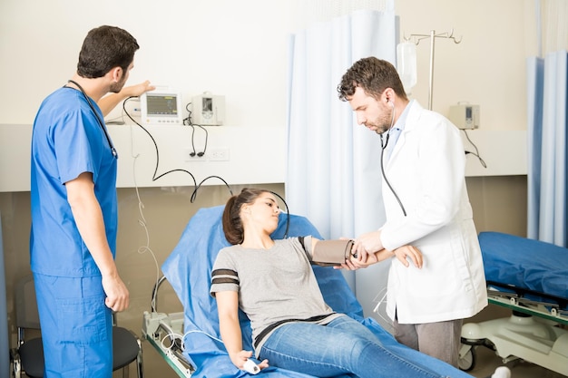 Junge Ärzte untersuchen eine Patientin und messen ihren Blutdruck in einem Krankenhaus