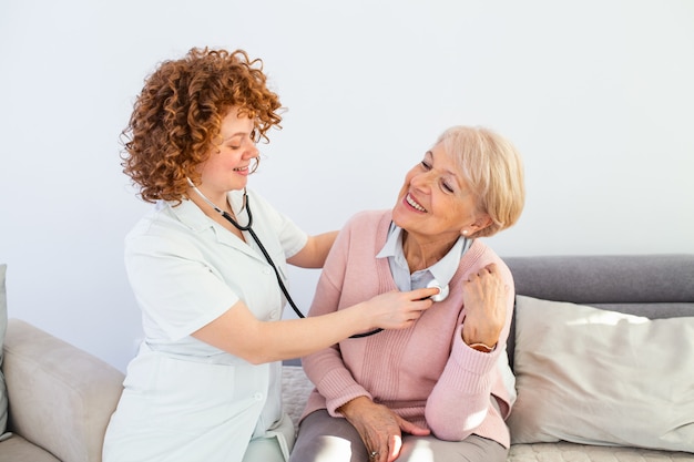 Junge Ärztin, die ältere Patientin untersucht. Junge Frau Doktor, die weißen Mantel trägt, der ältere Frau untersucht.