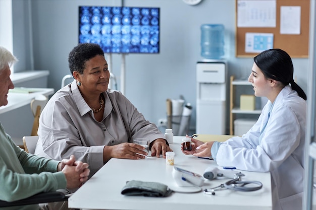 Junge Ärztin, die älteres Paar im Klinikbüro berät