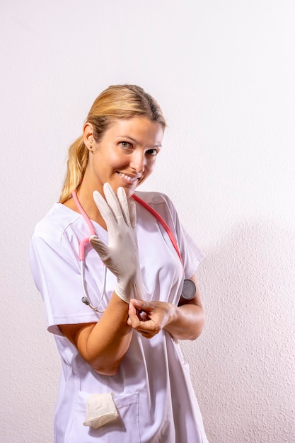 Junge Ärztin, die weiße Handschuhe auf weißem Hintergrund anzieht