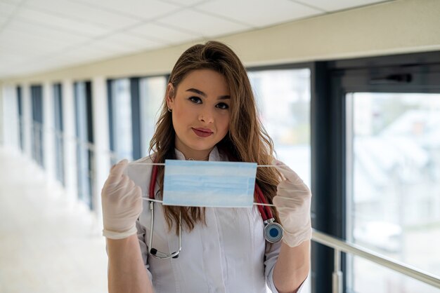 Junge Ärztin oder Krankenschwester, die eine Maske zum Schutz gegen Coronavirus COVID-19 setzt