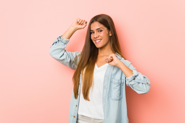 Junge schlanke Frau, die einen besonderen Tag feiert, springt und hebt Arme mit Energie