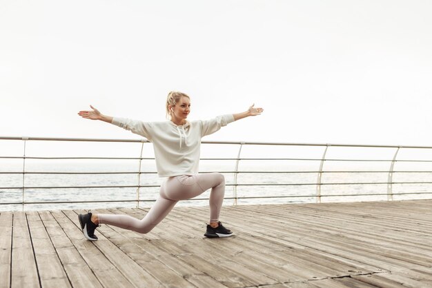 Junge, schlanke Frau, die Yoga-Asana-Übungen am Strand praktiziert. Fitness Mädchen. Krieger 2-Pose