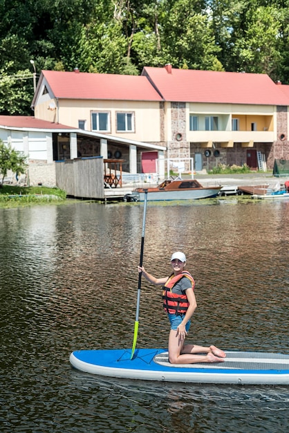 Junge schlanke Frau fährt mit einem SUP-Board auf dem Stadtsee