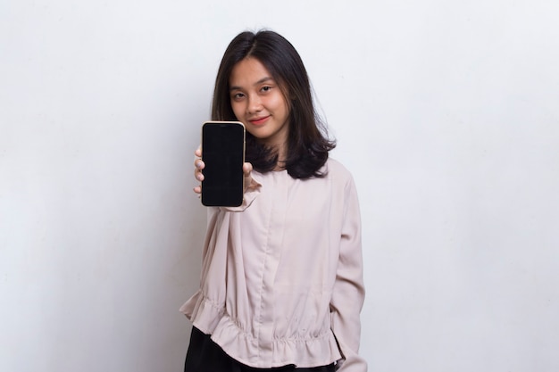 Junge schöne asiatische Frau demonstriert Handy isoliert auf weißem Hintergrund