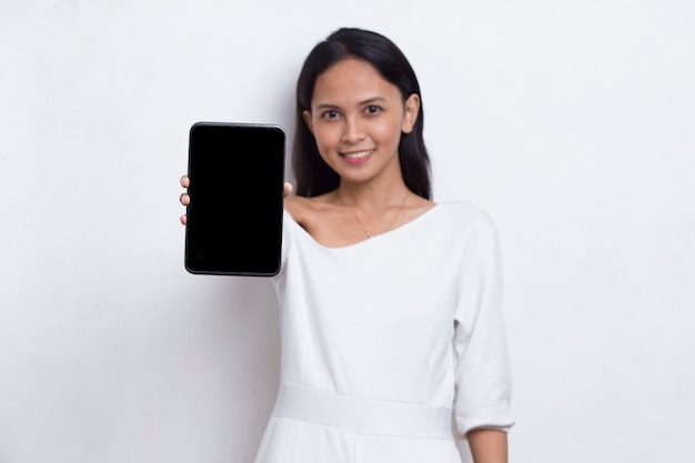 Junge schöne asiatische Frau demonstriert Handy isoliert auf weißem Hintergrund