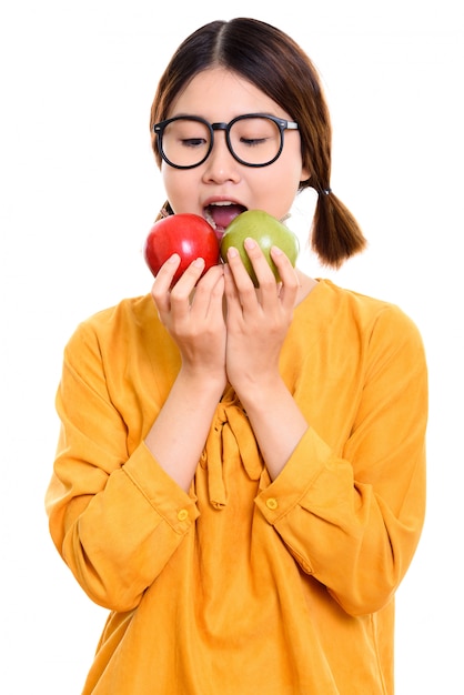 junge schöne asiatische Frau, die roten Apfel und grünen Apfel isst