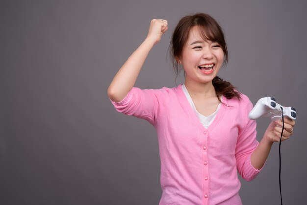 Junge schöne asiatische frau, die spiele mit gamecontroller spielt
