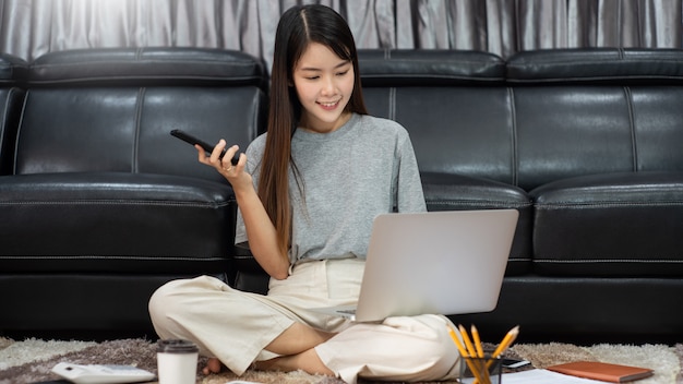 Junge schöne asiatische Frau, die zu Hause arbeitet