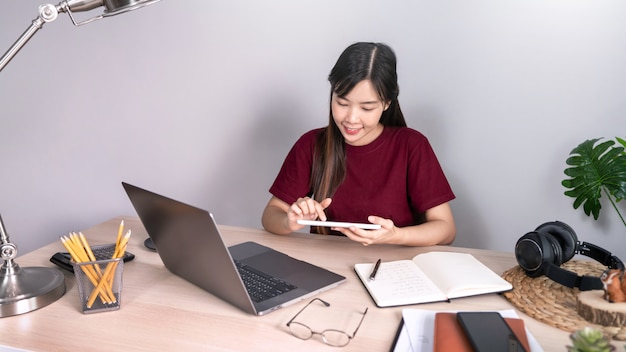 Junge schöne asiatische Frau, die zu Hause arbeitet