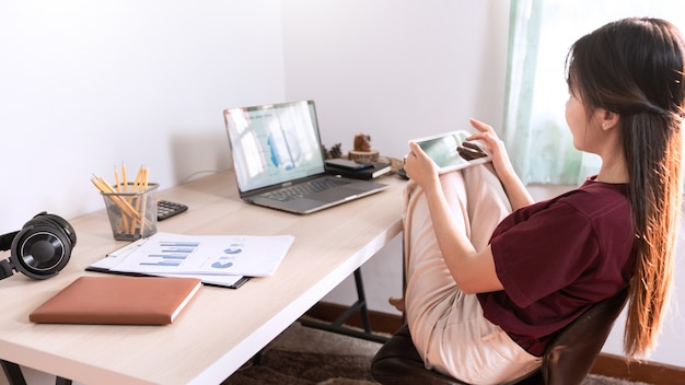 Junge schöne asiatische Frau, die zu Hause arbeitet