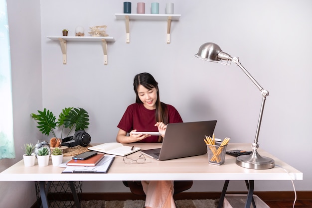 Junge schöne asiatische Frau, die zu Hause arbeitet