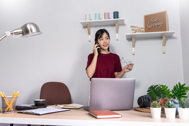 Junge schöne asiatische Frau, die zu Hause arbeitet