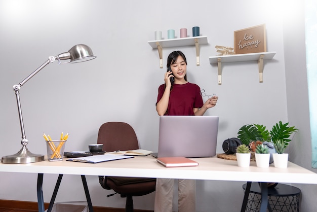 Junge schöne asiatische Frau, die zu Hause arbeitet