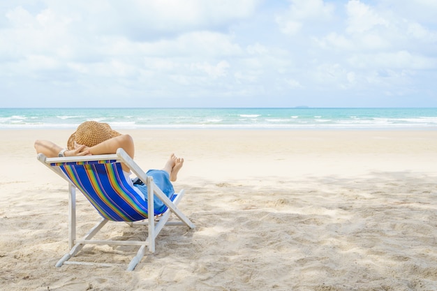 Junge schöne asiatische Frau entspannen in der Sonne auf Stühlen am Strand nahe dem Meer.