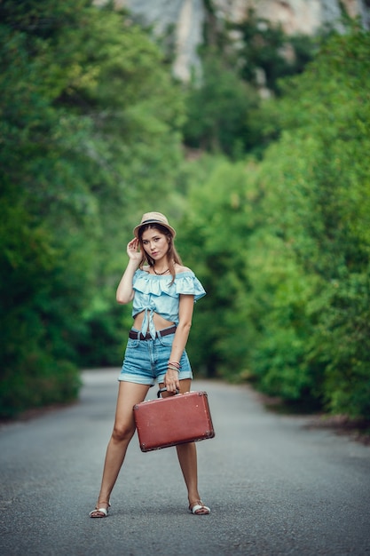 Junge schöne asiatische Frau im Hippie-Stil. reist per Anhalter. Straße in den Bergen.