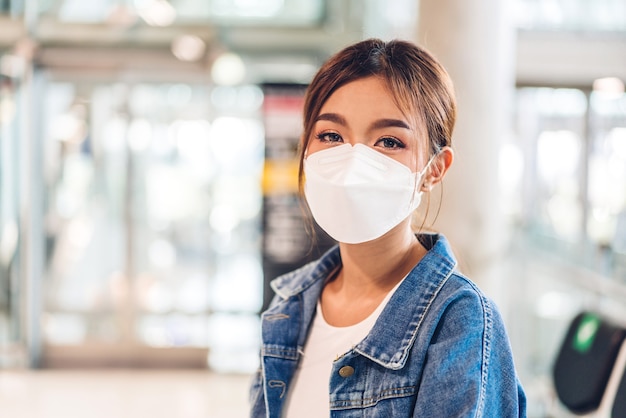 Junge schöne asiatische Frau in Quarantäne für Coronavirus mit chirurgischem Gesichtsschutz mit sozialer Distanzierung im city.covid19-Konzept
