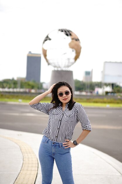 Junge schöne asiatische Frau trägt kariertes Hemd und blaue Jeans posiert im Freien