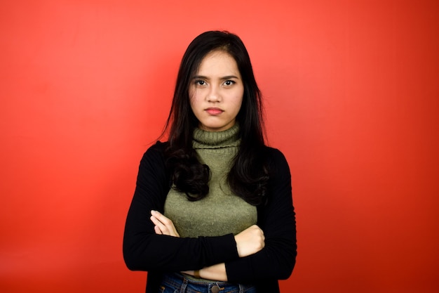 Junge schöne asiatische Frauen mit schwarzem Pullover wütend auf rot isolierten Hintergrund