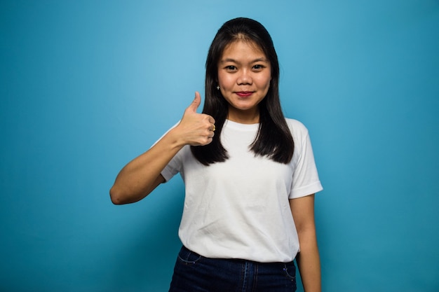 Junge schöne asiatische Frauen mit weißem T-Shirt mit blauem isoliertem Hintergrund Daumen hoch Geste