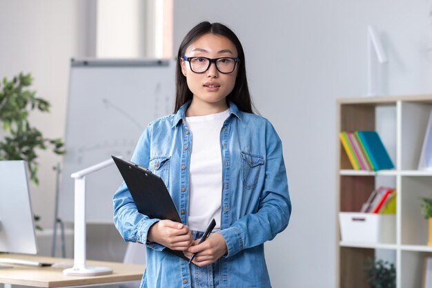 Junge schöne asiatische Geschäftsfrauberaterin, die im Büroporträt eines Angestellten arbeitet