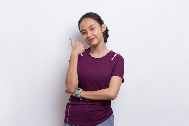 Junge schöne asiatische sportliche Frau, die eine Daumen-hoch-OK-Geste auf weißem Hintergrund zeigt