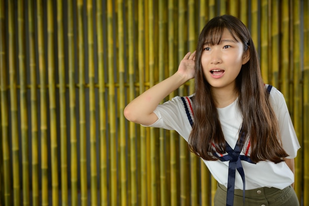 Junge schöne asiatische Teenager-Mädchen gegen Bambuszaun