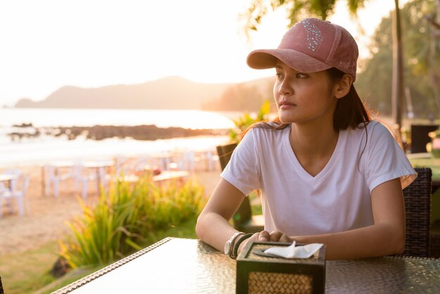 Junge schöne asiatische Touristenfrau, die am Strand entspannt