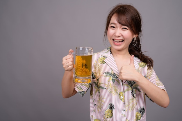 Junge schöne asiatische Touristenfrau, die Glas Bier hält