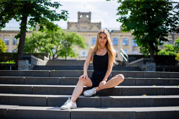 Junge schöne blonde sportliche Frau in einem schwarzen Trägershirt und in schwarzer Strumpfhose