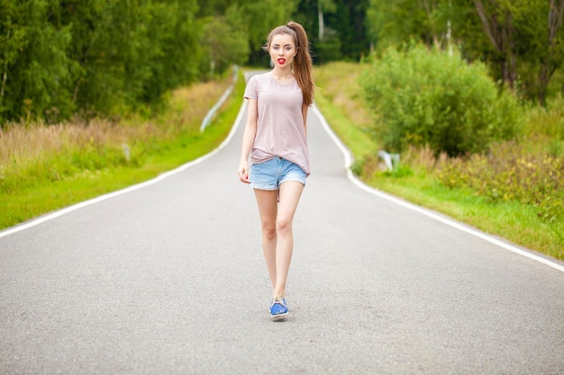 Foto junge schöne braunhaarige frau in kurzen blauen jeans, die auf der straße geht