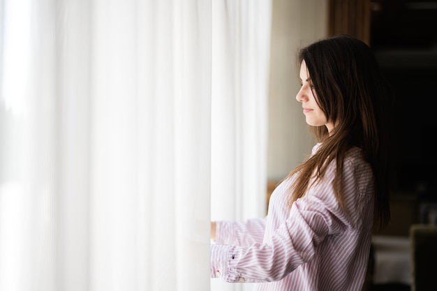 Junge schöne brünette Frau am Fenster, heller Hintergrund