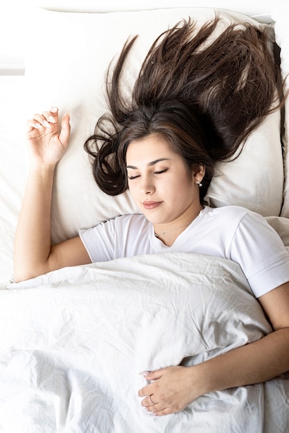 Junge schöne brünette Frau, die im Bett schläft