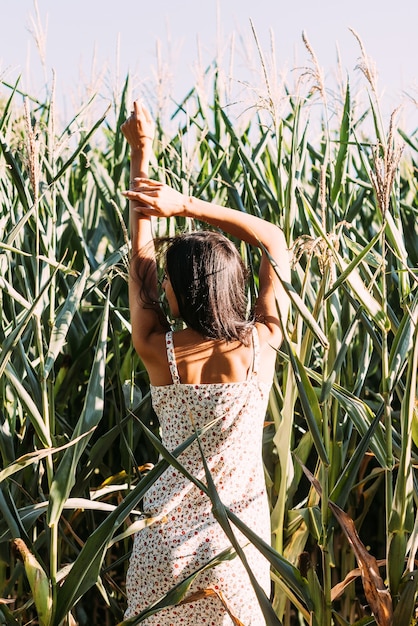 Junge schöne Brünette in einem eleganten Sommeroutfit und Strohhut in den Sonnenstrahlen der Natur