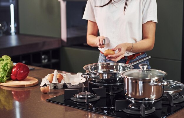 Junge schöne Brünette in Freizeitkleidung bereitet tagsüber gesundes Essen in der Küche zu