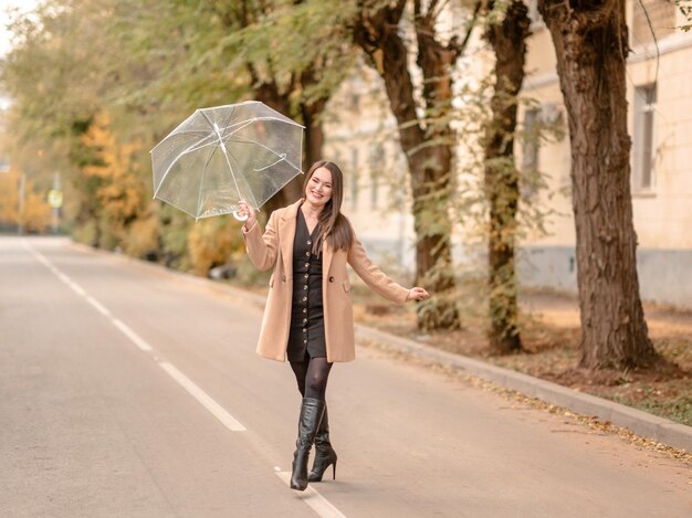 Junge schöne Brünette mit langen Haaren hält einen weißen Regenschirm. Herbst in der Natur