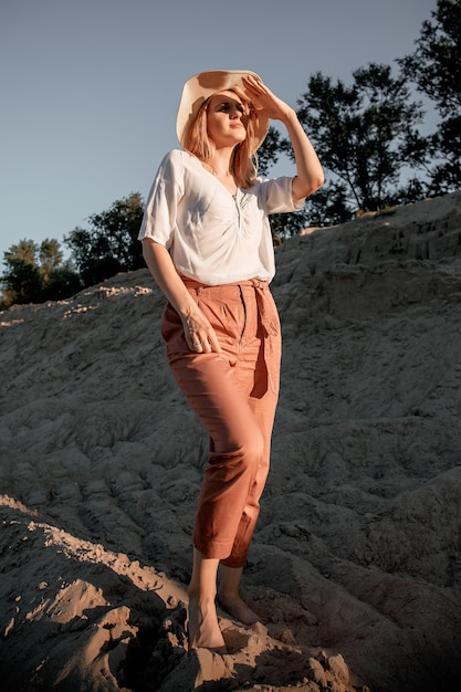 Foto junge schöne einsame frau mit langen haaren herein mit strohhut. ein einsames mädchen geht die sanddünen hinunter.