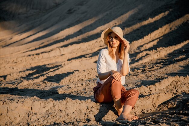 Junge schöne einsame Frau mit langen Haaren herein mit Strohhut. Ein einsames Mädchen geht die Sanddünen hinunter.