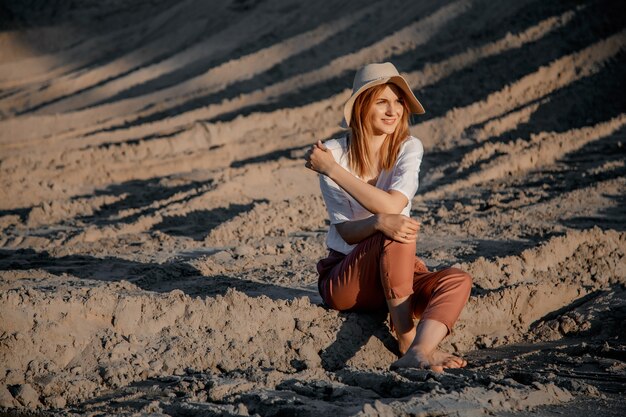 Junge schöne einsame Frau mit langen Haaren herein mit Strohhut. Ein einsames Mädchen geht die Sanddünen hinunter.