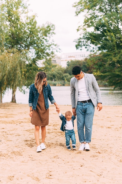 junge schöne Familie, die eine tolle Zeit in der Nähe eines Sees hat