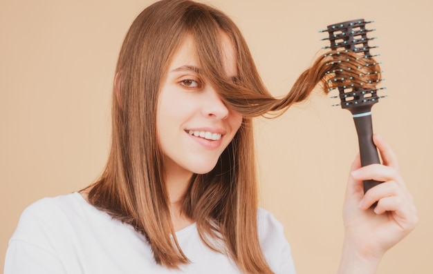 Junge schöne Frau, die braunes Haar kämmt Haarpflege Schöne brünette Frau, die Haare mit Haarbürste bürstet Gesundes Haar mit Kamm bürsten