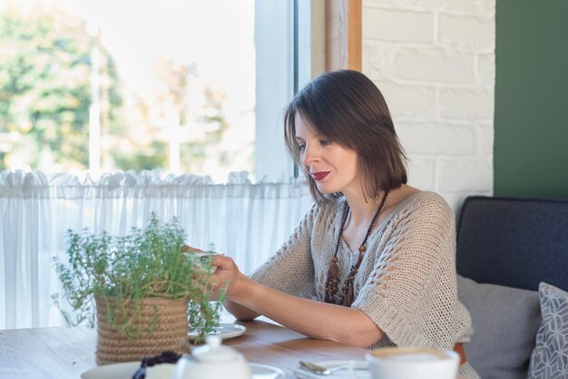 Junge schöne Frau, die Cappuccino im Café im Inneren genießt Schönes Mädchen, das heißen Tee in der Cafeteria genießt