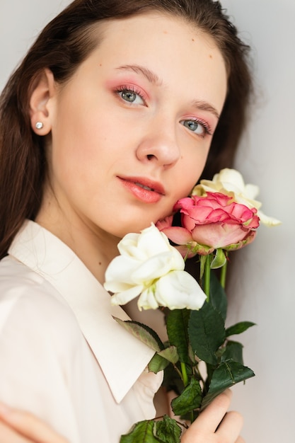 Junge schöne Frau, die einen Strauß roter Rosen riecht. Modeinnenfoto einer schönen lächelnden Frau mit dunklem Haar, die am Valentinstag einen großen Strauß roter Rosen hält