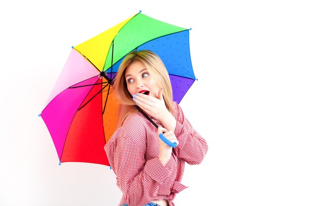 Junge schöne Frau, die farbigen Regenschirm auf weißem Hintergrund hält