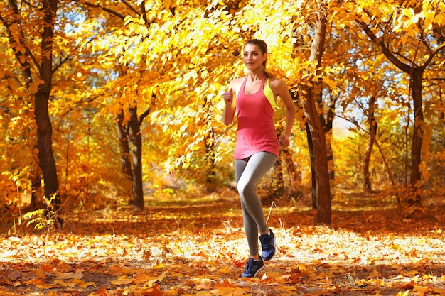 Junge schöne Frau, die im Herbstpark joggt